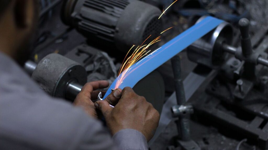 Close-up of hands grinding metal with sparks in an industrial workshop.