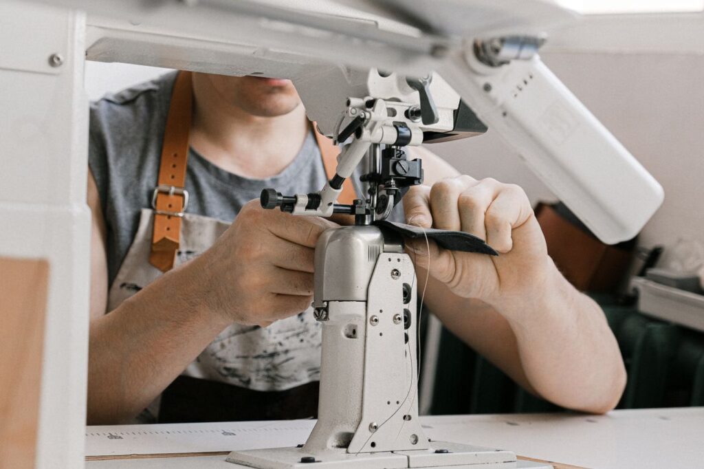 Close-up of an artisan carefully crafting leather with a sewing machine, emphasizing skill and precision.