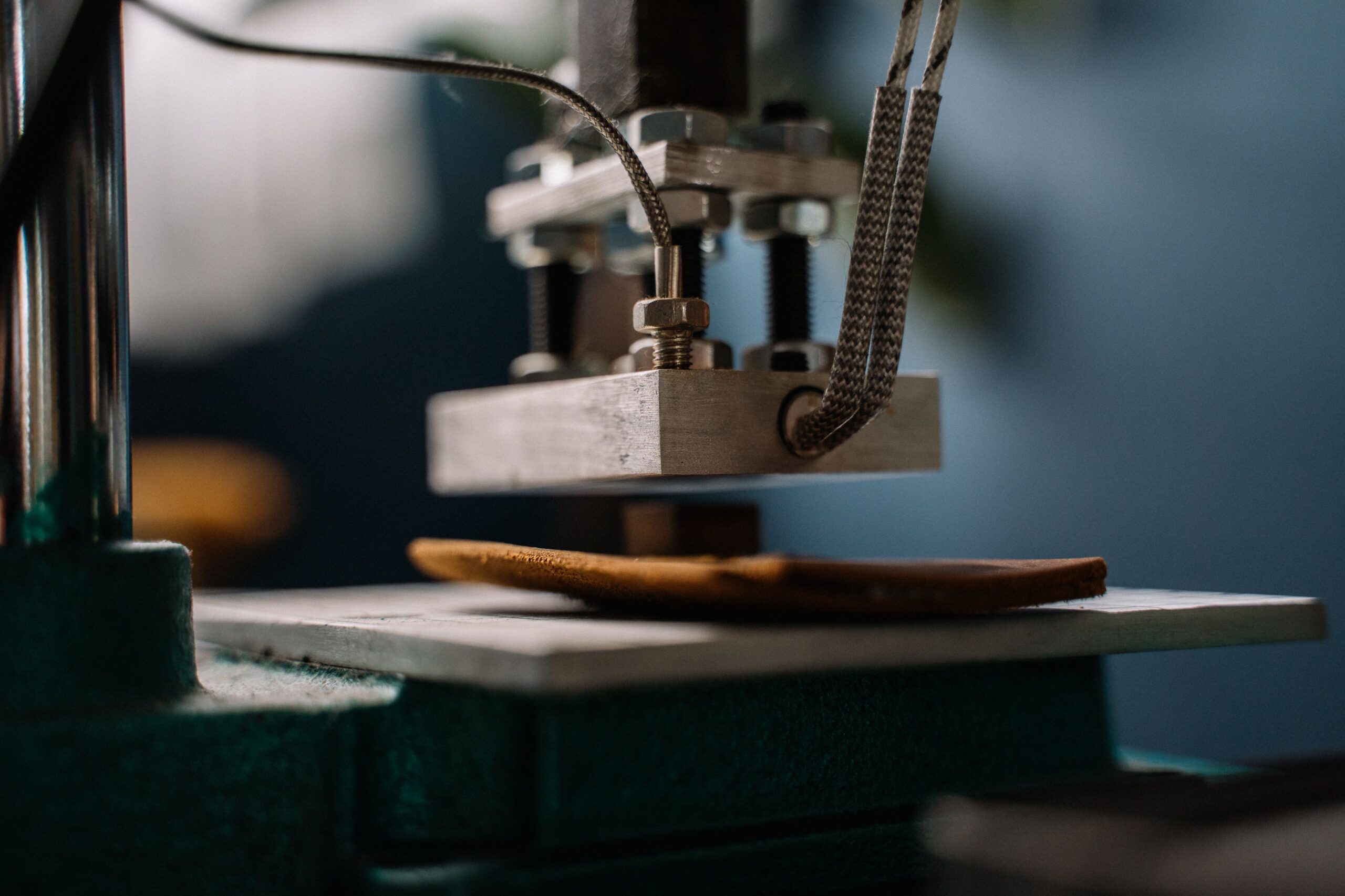 Detailed view of a leather embossing machine pressing leather, showcasing craftsmanship.
