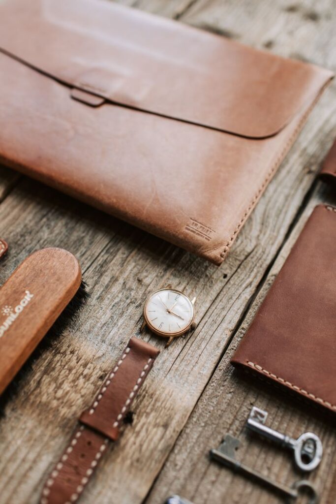Elegant leather accessories neatly arranged on rustic wooden surface, showcasing craftsmanship.