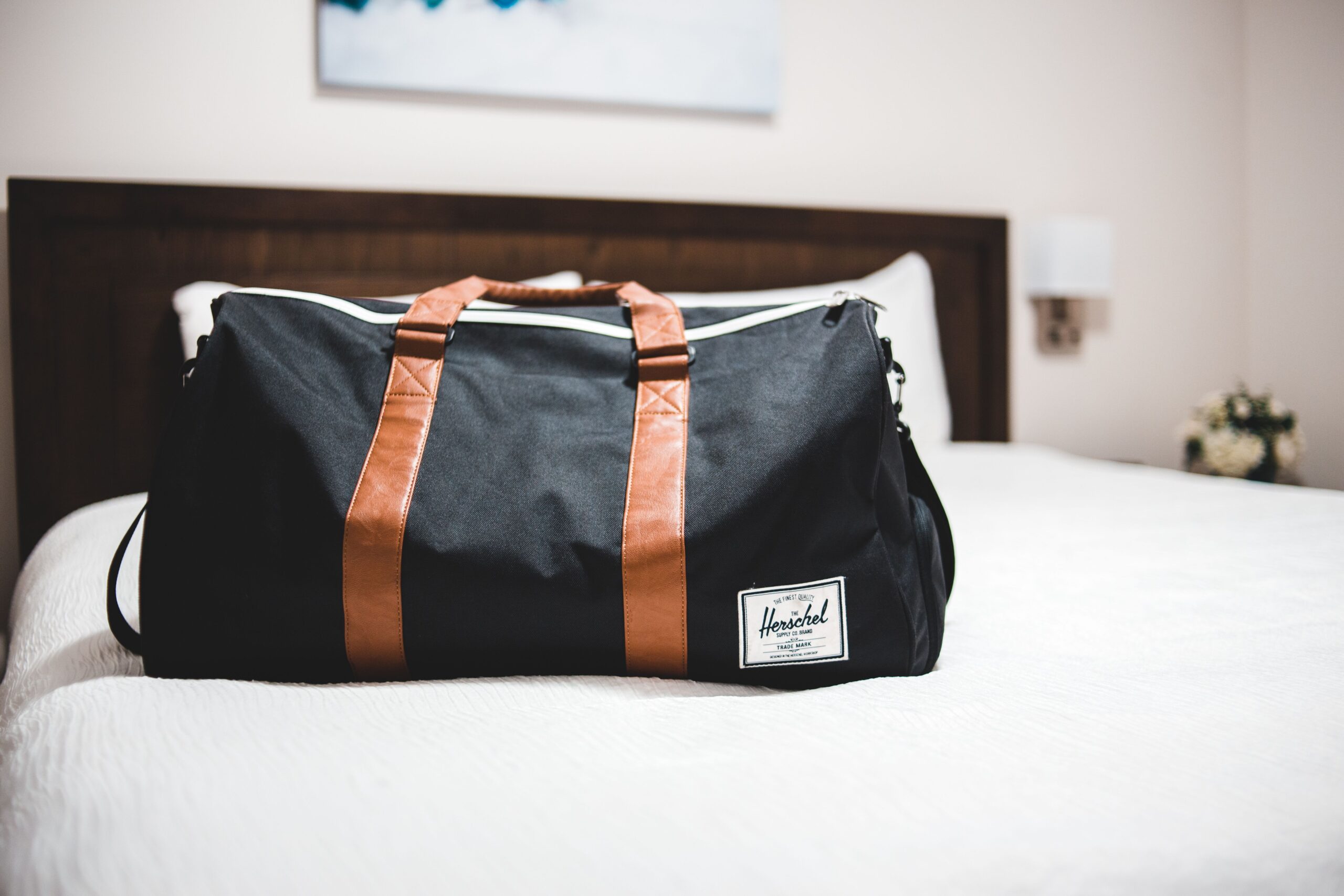 Contemporary baggage bag with inscription on white bed cover in light hotel room